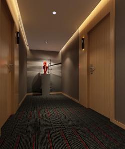 a hallway with a red figurine on a table and a door at Thank Inn Chain Hotel Hubei Huanggang Macheng Beihuan Road in Macheng