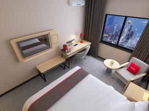 a small hotel room with a bed and a desk at Thank Inn Plus Hotel Jiangsu Nantong Rudong County Qianshuiwan Park in Jinjiazhuang