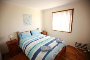 um quarto com uma cama com lençóis azuis e brancos em Waves & Wildlife Cottages Kangaroo Island em Stokes Bay