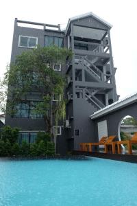a building with a swimming pool in front of a house at The Besavana Phuket - SHA Extra Plus in Phuket Town