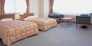 ein Hotelzimmer mit 2 Betten, einem Tisch und Stühlen in der Unterkunft Itoen Hotel in Ito