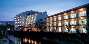 ein großes Gebäude mit beleuchteten Fenstern neben einem Fluss in der Unterkunft Itoen Hotel in Ito