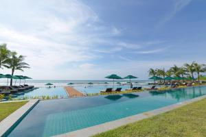 a swimming pool next to the ocean with umbrellas at Ocean Front Campgrounds in Ngwesaung