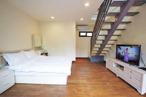 南庄的住宿－宜家園  ，一间卧室设有一张床、一台电视和楼梯。