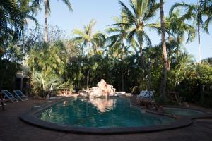 a swimming pool with a fountain in front of palm trees at Roebuck Bay Hotel in Broome