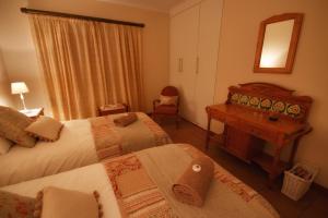 a bedroom with two beds and a desk and a mirror at Clarens Cottage 2 in Clarens