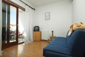Cette chambre dispose d'un canapé bleu avec un animal farci. dans l'établissement Apartments Sergio 1499, à Fažana