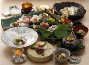 einen Tisch mit Teller mit Lebensmitteln und Schüsseln mit Lebensmitteln in der Unterkunft Yufuin Souan Kosumosu in Yufu