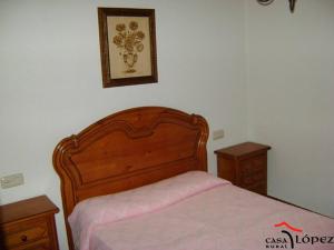 1 cama con cabecero de madera y 2 mesitas de noche en Casa Lopez en San Martín del Castañar