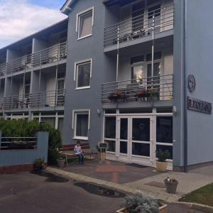 a woman sitting on a bench in front of a building at Solar Club Hotel in Sopron
