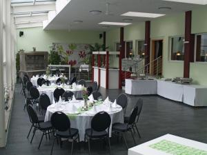 einen Bankettsaal mit weißen Tischen und schwarzen Stühlen in der Unterkunft Gästehaus Zum Stehling in Monschau