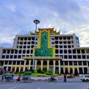 a large building with a green and yellow at Gold Yadanar Hotel in Mandalay