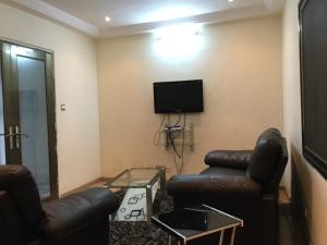 sala de estar con muebles de cuero y TV de pantalla plana en Julmarte en Lomé