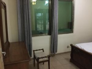 een slaapkamer met een bed, een stoel en een raam bij Julmarte in Lomé
