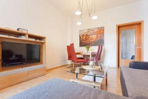 ein Wohnzimmer mit einem TV und einem Tisch mit Stühlen in der Unterkunft Ferienwohnung City in Erfurt