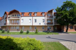 ein Apartmenthaus mit einem Baum davor in der Unterkunft Zoli Apartmanok-Anita Kölcsey 34-36 in Hajdúszoboszló