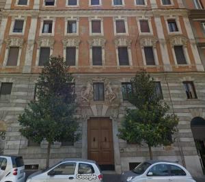 dwa samochody zaparkowane przed budynkiem z drzwiami w obiekcie Wake At Rome w Rzymie