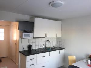 cocina con armarios blancos, fregadero y microondas en Fjällstuga en Idre