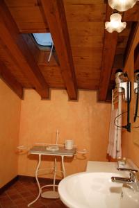 a bathroom with a white sink and wooden ceilings at Agriturismo Macesina in bedizzol