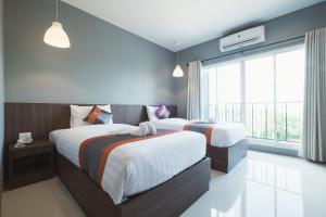 ein Schlafzimmer mit zwei Betten und einem großen Fenster in der Unterkunft Hansanan Hotel in Phitsanulok + 15 Fotos