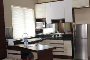 a kitchen with white cabinets and a stainless steel refrigerator at MTC Mega Mas Apartment in Manado