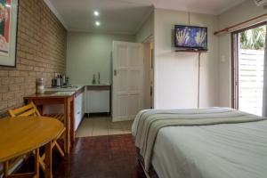 a bedroom with a bed and a table and a kitchen at Carrington Guest House in Durban