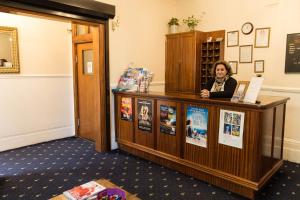 une femme debout à un comptoir dans une pièce dans l'établissement Europa House Hotel, London Paddington, à Londres