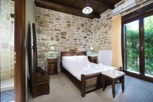 a bedroom with a bed and a stone wall at Villa Platanos in Plátanos