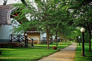 a path next to a house with trees and a building at Manyatta Camp in Voi