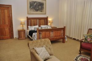 a bedroom with a bed and a couch and a chair at Huisie Ommie Hoek in Uniondale