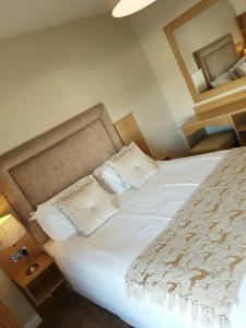 1 dormitorio con 1 cama con sábanas blancas y espejo en Belfast House, en Cookstown