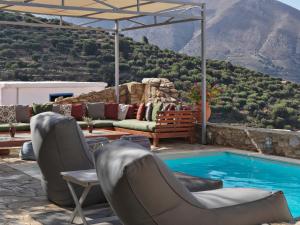 a patio with chairs and a pool with a mountain at Cressa Ghitonia Village in Sfáka