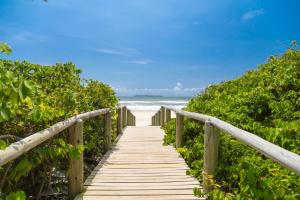 a wooden boardwalk leading to the beach at Residencial Onda Azul in Bombinhas