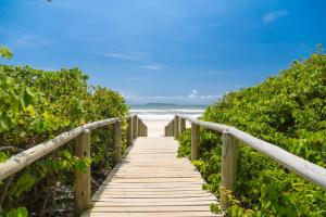 un paseo marítimo de madera que conduce a la playa en Residencial Onda Azul, en Bombinhas