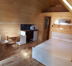 Habitación con cama, mesa y cocina. en Camping Pico De La Miel, en La Cabrera