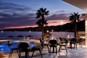 a patio with tables and chairs with a view of the water at Poseidon of Paros Hotel & Spa in Chrissi Akti