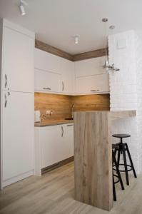 a kitchen with white cabinets and a counter with a stool at kameralny apartament in Olsztyn