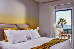 a bedroom with a bed with a view of the ocean at Poseidon of Paros Hotel & Spa in Chrissi Akti