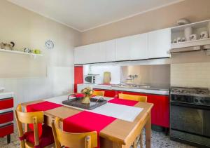 アベトーネにあるAppartamento Il Pungitopoのキッチン(赤と白のキャビネット、木製テーブル付)