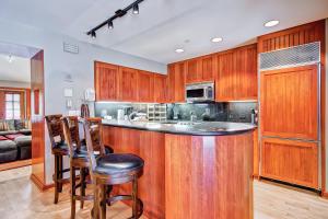 a kitchen with wooden cabinets and a bar with bar stools at Village Hall by East West Hospitality in Beaver Creek