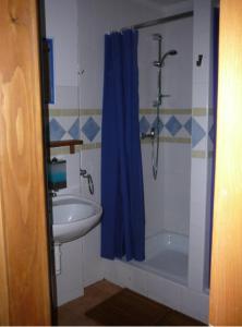 a bathroom with a sink and a shower with a blue shower curtain at Hostel Postel in Český Krumlov