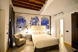 a bedroom with a large bed and a chair at Legado Alcazar Hotel in Seville