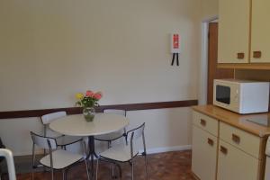 uma cozinha com uma mesa e cadeiras e um micro-ondas em Honeysuckle Bungalow em Torquay