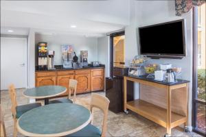 a living room with two tables and a flat screen tv at Howard Johnson by Wyndham Vicksburg in Vicksburg