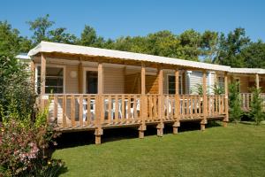 a large wooden house with a large deck at Camping Les Chèvrefeuilles in Royan