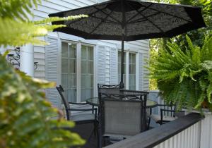 ナイアガラ・オン・ザ・レイクにあるButler Creek Houseのテーブルと椅子と傘のあるパティオ