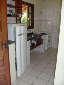 a kitchen with a sink and a white refrigerator at Chalés Carioca Prumirim Ubatuba in Ubatuba