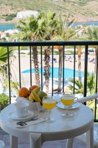 a table with two glasses of orange juice on a balcony at TRH Tirant Playa in Fornells