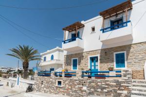 a building with blue windows and a palm tree at To Petrino in Koufonisia