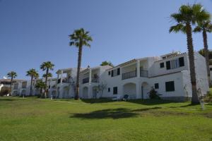 a large white building with palm trees in front of it at TRH Tirant Playa in Fornells